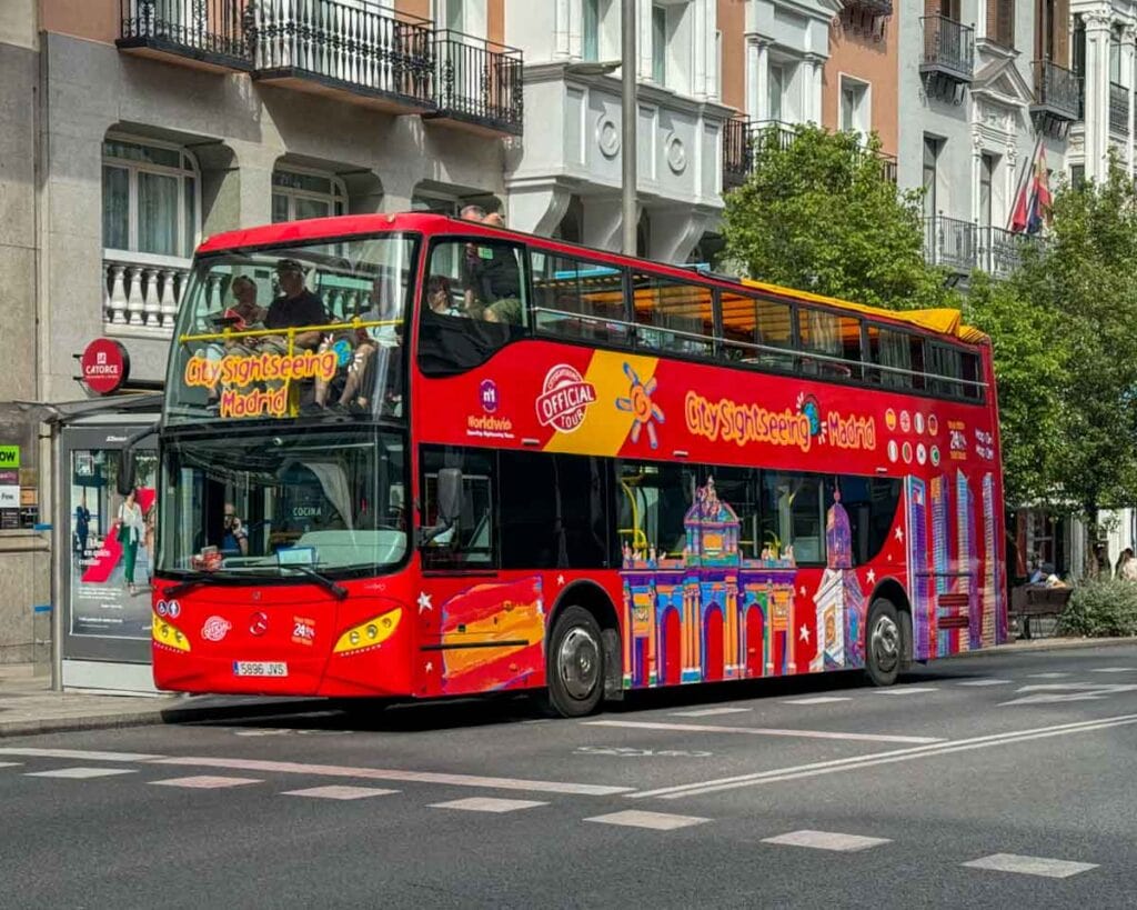 a red double decker bus with signage identifying it as a hop on hop off tourist bus servuce