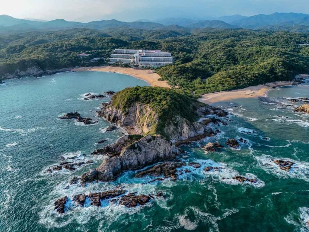 rock formation in the turquoise sea with a view of the resort in the backgrouns